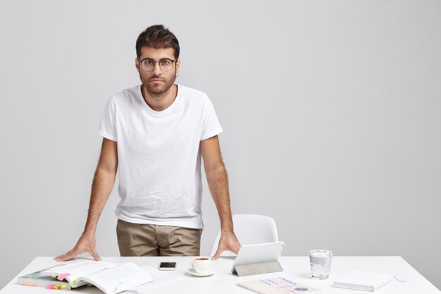 Stylish young man standing near desk