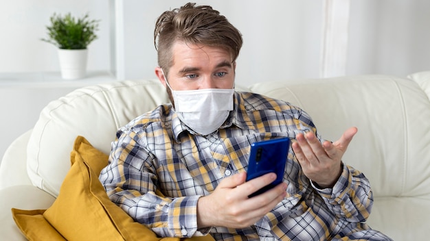 Stylish young man with face mask holding mobile phone