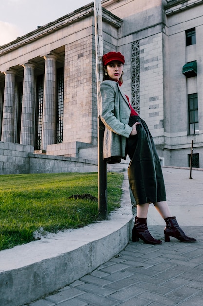 Free Photo stylish young woman leaning on pillar with hands in her pocket