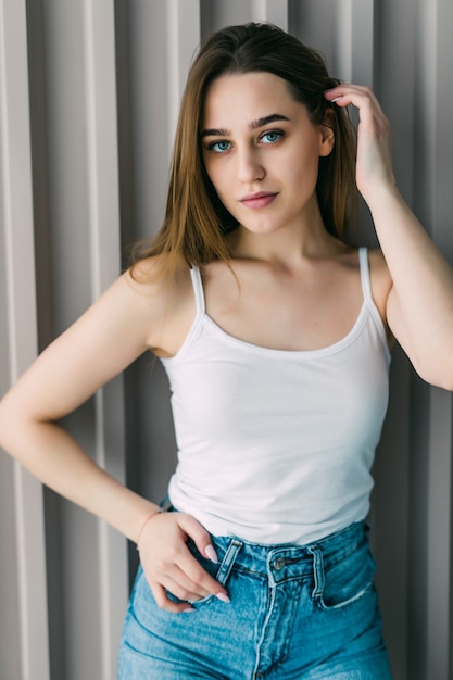 Stylish young woman standing in loft apartment smiling with hand in hair