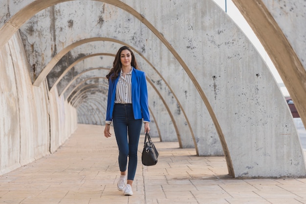 Free Photo stylish young woman with handbag walking