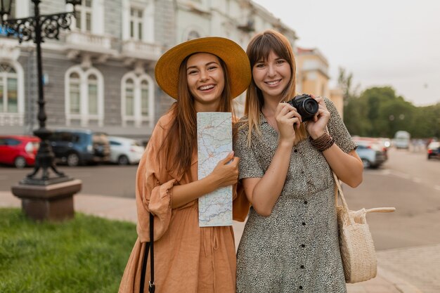 Stylish young women traveling together in Europe dressed in spring trendy dresses and accessories