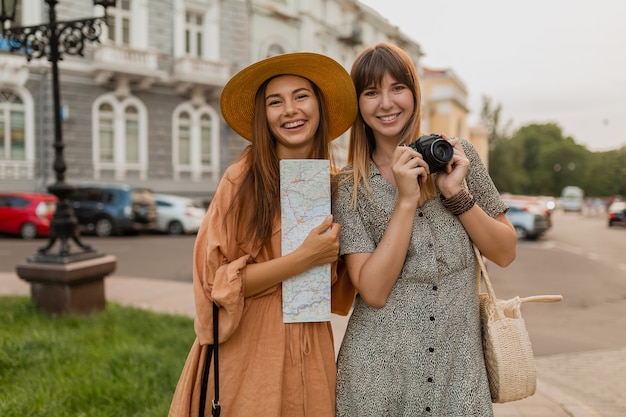 Stylish young women traveling together in Europe dressed in spring trendy dresses and accessories