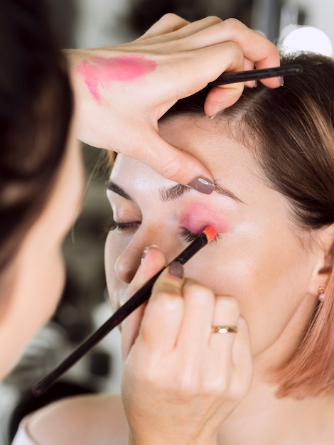 Stylist applying pink eyeshadow on model