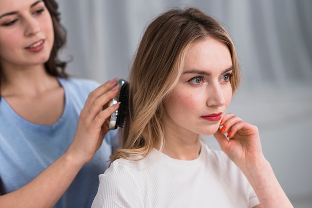 Stylist straightens hair blond woman