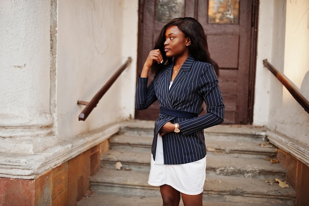 Free photo success stylish african american woman in jacket and skirt against old wooden door