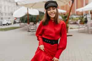 Free photo successful attractive girl with good style walking down street. portrait of european model in fashionable scarlet satin dress