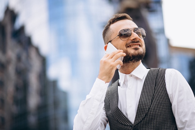 Successful business man by the skyscraper talking on the phone