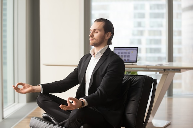 Free Photo successful businessman meditating at workplace