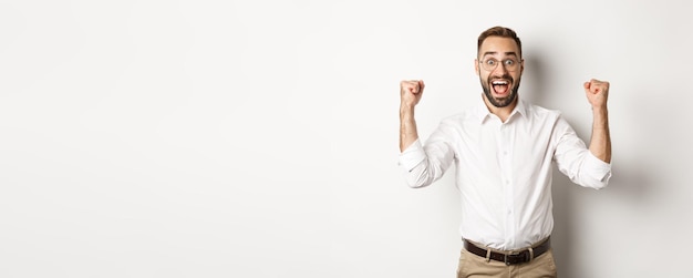 Free photo successful businessman rejoicing raising hands up and celebrating victory winning something standing