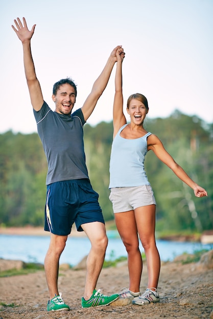 Successful couple of young athletes raising arms