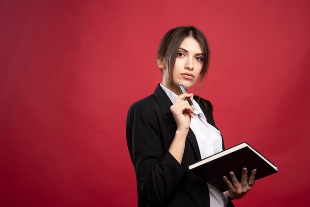 Successful employee posing on red background. 