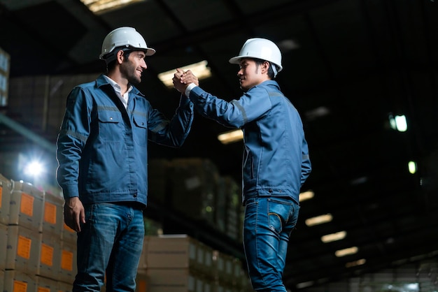 Free photo successful engineer teamwork casual positive converation working together in warehouse factorymale worker with safety helmet checking quantity quality of product boxes on storage shelf in warehouse