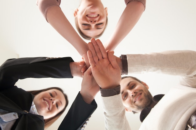 Successful united business team put hands together, view from below