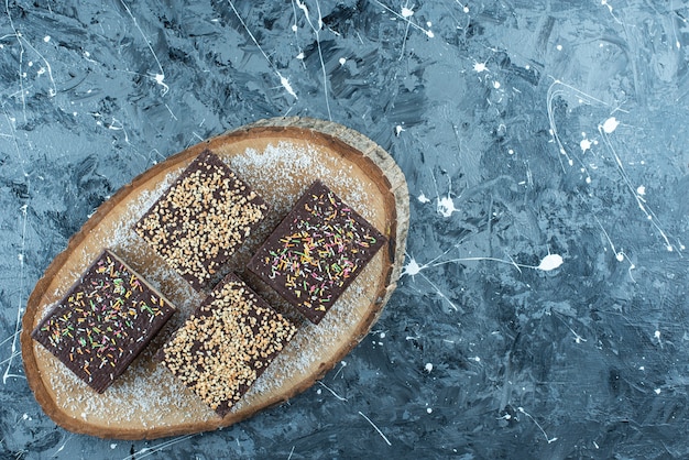 Free photo sugar sprinkle on a chocolate waffle on a board , on the blue table.