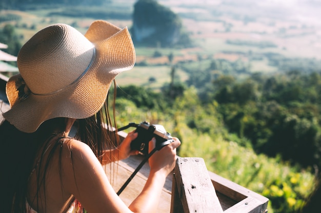 Summer beautiful girl holding a mountain view camera