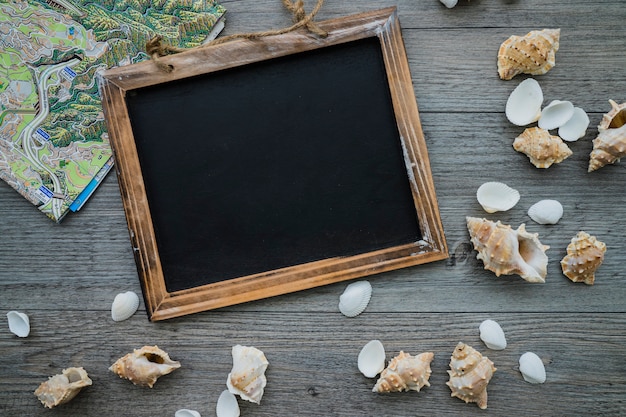 Summer composition with blank slate, seashells and map