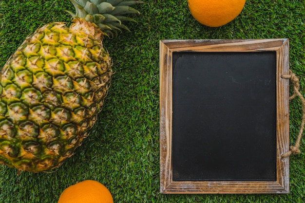 Free photo summer composition with slate, pineapple and oranges