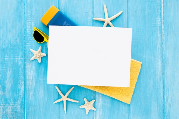 Summer flat lay composition with starfish cream bottle, glasses and towel and blank cardboard