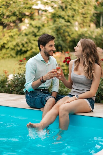 Summer holidays, people, romance, dating concept, couple drinking sparkling wine while enjoying time together sitting at the pool