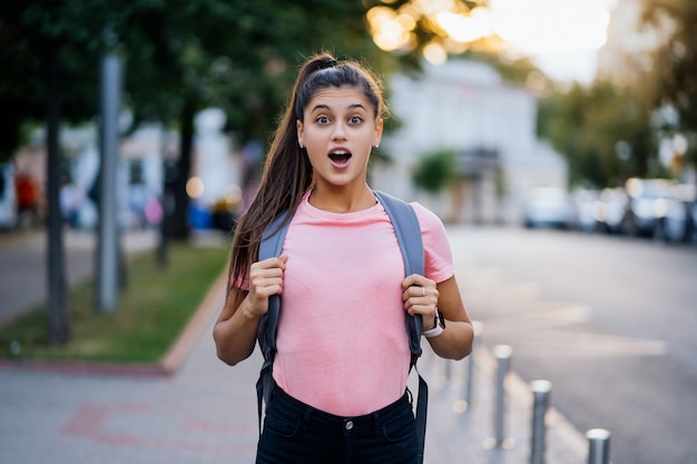 Summer lifestyle fashion portrait of young surprised woman walking on the street