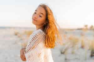 Free photo summer photo of small girl in stylish boho outfit posing on the beach warm sunset colors wacation and  travel concept