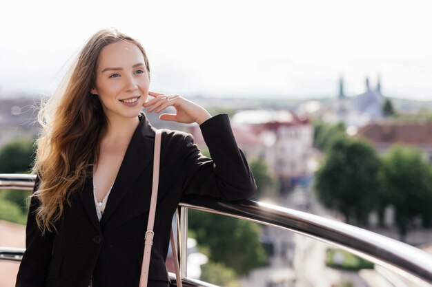 Summer portrait of young woman relaxing on the roof top terrace over european city view background.