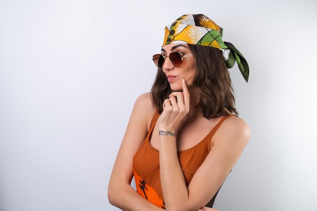 Summer portrait of a young woman in a sports swimsuit headscarf and sunglasses