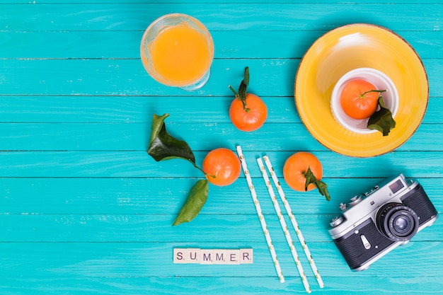 Free Photo summer set with tangerines and juice and camera on wooden surface