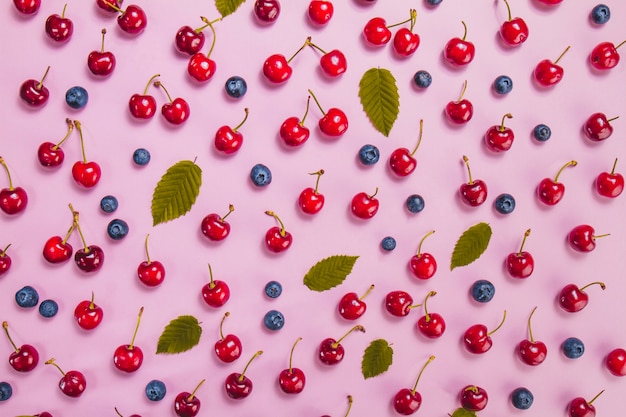 Free photo summer surface with cherries, blueberries and green leaves