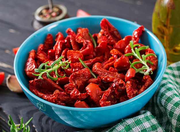 Free photo sun dried tomatoes with herbs and garlic in  bowl on wooden table. italian food.