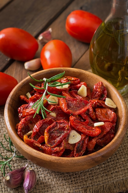 Sun-dried tomatoes with herbs and garlic in wooden bowl