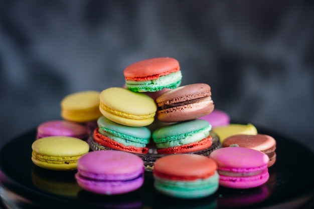 Sun rays lie over colorful macaroons on glass plate 