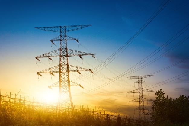 Sun setting behind the silhouette of electricity pylons