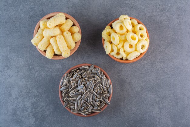 Sunflower seeds, corn sticks and corn ring on bowls , on the marble surface