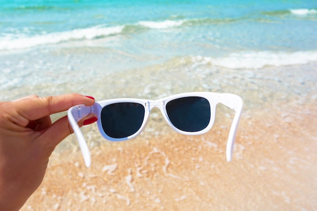 Free photo sunglasses in hand on background of the beach