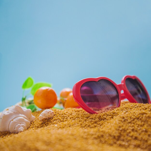 Sunglasses and oranges on sand