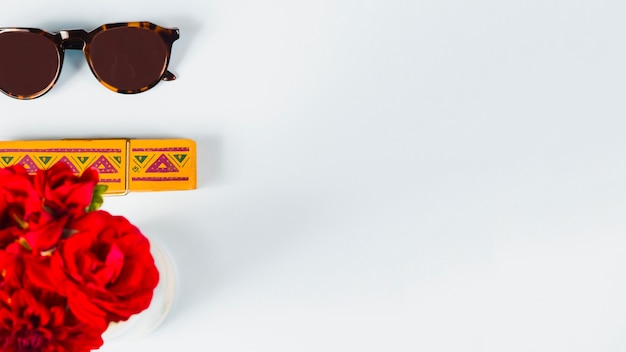 Sunglasses and red roses on white background