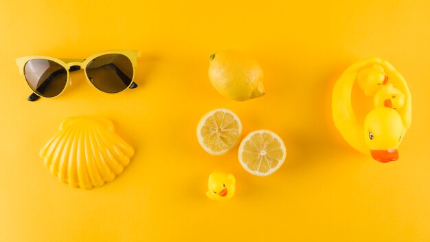 Sunglasses; scallop; lemon and rubber duck on yellow backdrop