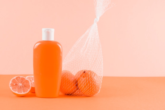 Free photo sunscreen lotion bottle and grapefruits on colored backdrop