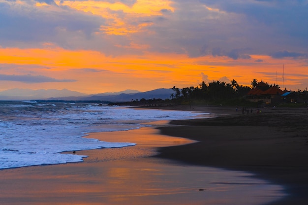 Sunset on the ocean, bright sunset colors, reflection on the water, palm trees and mountains on the horizon. Natural background.