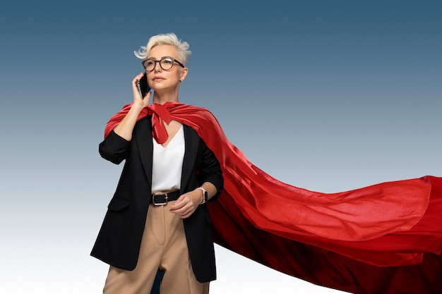 Free photo superwoman with cape talking on smartphone