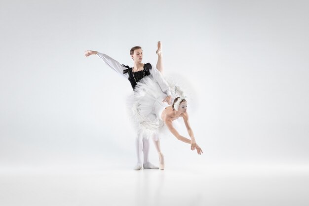 Supporting. Graceful classic ballet dancers dancing isolated on white studio background. Couple in tender clothes like a white swan characters. The grace, artist, movement, action and motion concept.