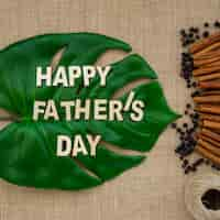 Free photo surface with palm leaf and cinnamon sticks for father's day