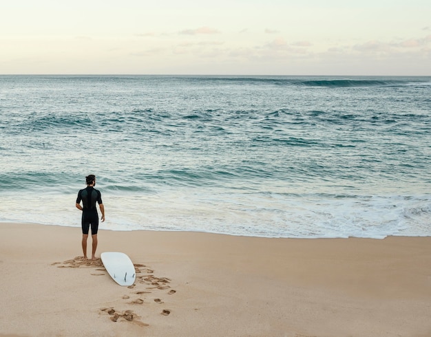 Free photo surfer man looking at the sea horizontal long shot