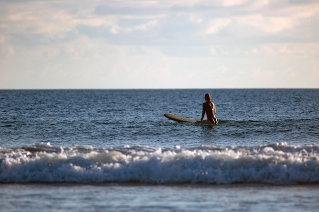 Surfer sitting in the ocean at sunset