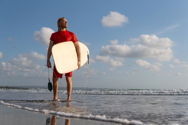 Free photo surfer walking along the beach. bali