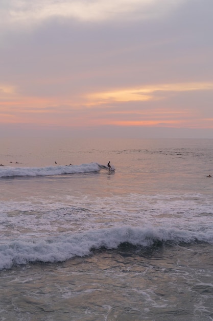 Surfers catch waves at sunset in the ocean. Surfing background