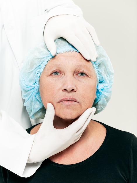 Free photo surgeon doing skin check on mid age woman before plastic surgery