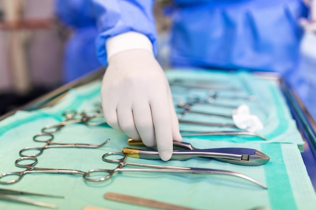 Free photo surgeon picking up surgical tool from tray surgeon is preparing for surgery in operating room he is in a hospital